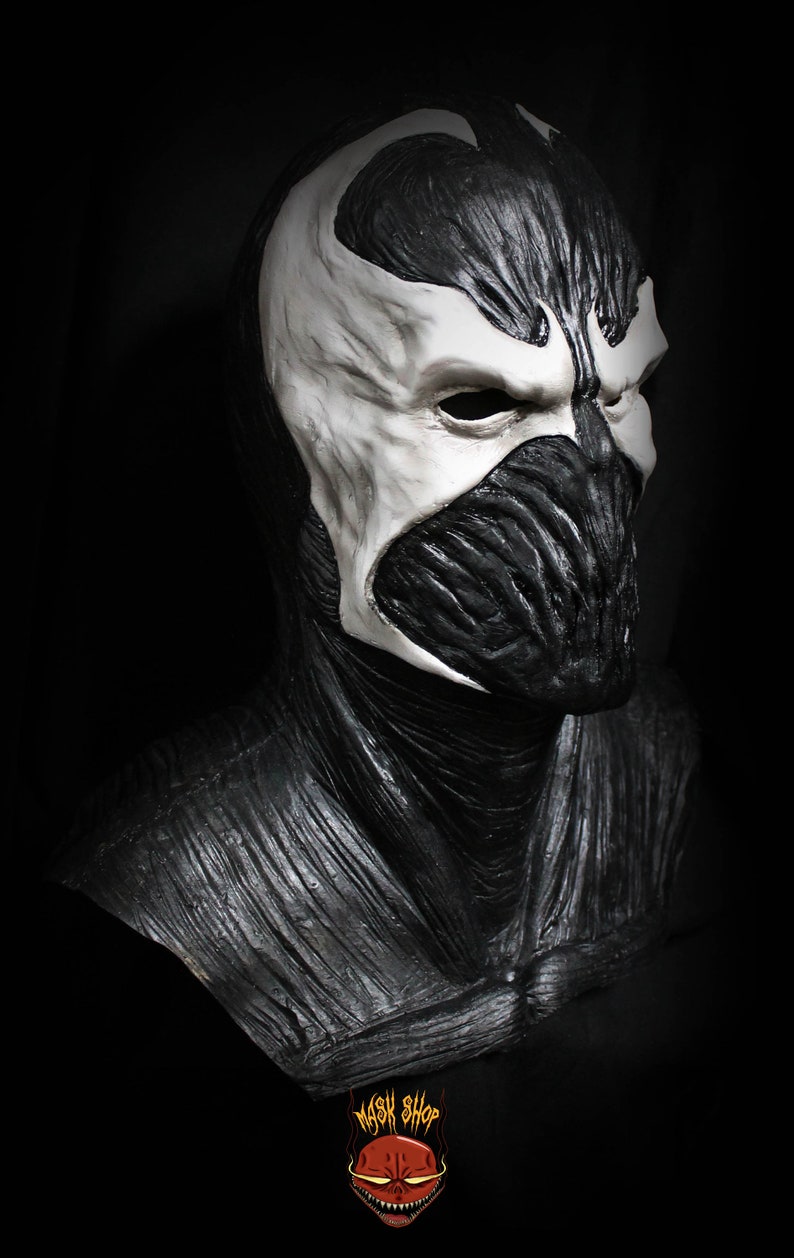 May include: A black and white latex mask of a character with a detailed, textured design. The mask covers the head and neck, with a white face and black eyes.