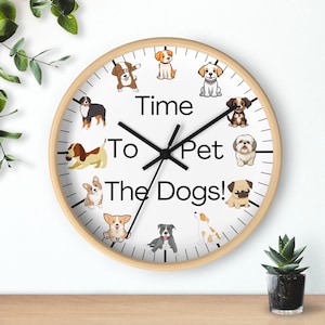 Könnte beinhalten: Eine weiße Uhr mit schwarzen Zeigern und einem Holzrahmen. Das Zifferblatt der Uhr zeigt den Text "Time To Pet The Dogs!" und zeigt Cartoon-Hunde um das Zifferblatt der Uhr.