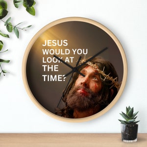 Puede incluir: Un reloj de pared redondo de madera con fondo marrón y una imagen de Jesús con una corona de espinas. La esfera del reloj tiene agujas negras y el texto "JESUS WOULD YOU LOOK AT THE TIME?" en blanco.