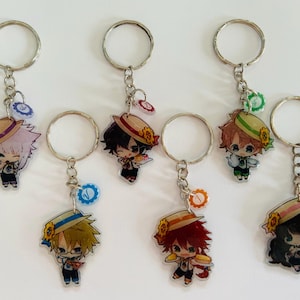 May include: Six keychains featuring anime-style characters with straw hats and different colored hair. Each keychain has a silver ring and a small charm with a gear design.