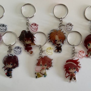 May include: Set of seven anime character keychains with silver key rings. Each keychain features a different character with a colorful design and a small circular charm with a floral design.