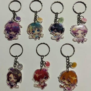 Puede incluir: Conjunto de diez llaveros de personajes de anime. Cada llavero presenta un personaje diferente con un diseño colorido. Los llaveros están unidos a llaveros de plata.