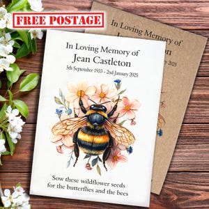 May include: A white memorial card featuring a bee and floral design, with the text "In Loving Memory of Jean Castleton" and dates. The card also includes the phrase "Sow these wildflower seeds for the butterflies and the bees". A brown card is visible behind it.