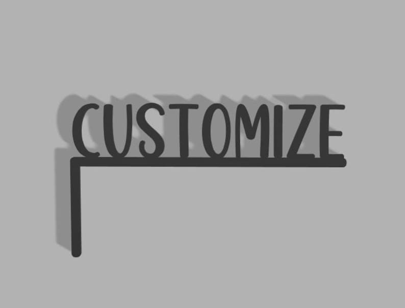 Puede incluir: Un gr&aacute;fico en blanco y negro con la palabra "CUSTOMIZE" en una fuente estilizada. La palabra est&aacute; sobre una l&iacute;nea negra que se extiende hacia la izquierda, formando una esquina.