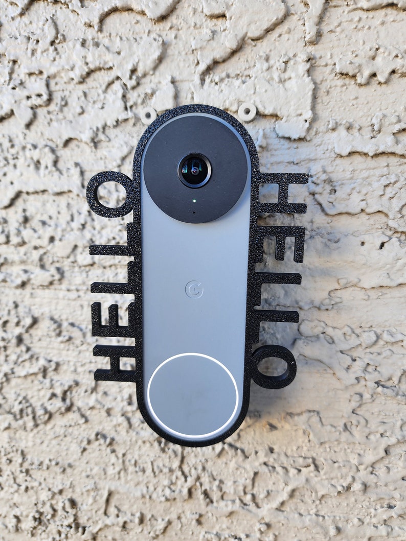 May include: A black and gray Google Nest Hello doorbell with a "HELLO" sign on either side. The doorbell is mounted on a textured wall.