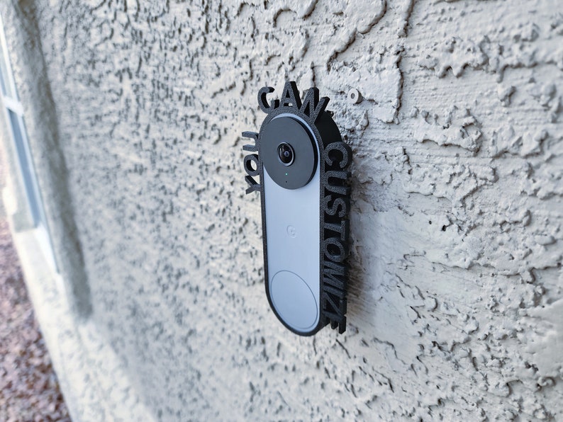 May include: A black custom-made door sign with the words "Gawk" and "Customize" surrounding a white and gray doorbell camera.