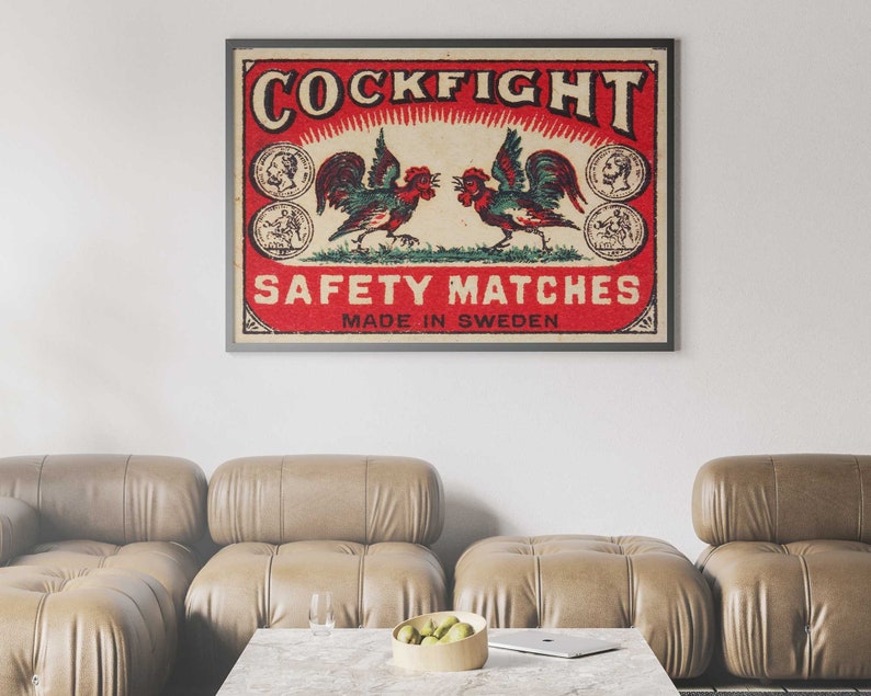 以下が含まれることがあります： 赤い背景に「COCKFIGHT SAFETY MATCHES MADE IN SWEDEN」という文字が書かれた、ビンテージのマッチ箱のラベル。ラベルの中央には、翼を広げて向き合った2羽の雄鶏が描かれている。