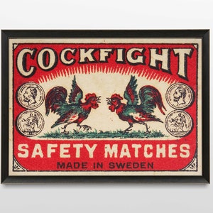 以下が含まれることがあります： 赤い背景に「COCKFIGHT SAFETY MATCHES MADE IN SWEDEN」という文字が書かれた、ビンテージのマッチ箱のラベル。2羽の雄鶏が向き合っていて、一方は緑と赤、もう一方は緑と青。雄鶏は小さな円形の画像で囲まれています。