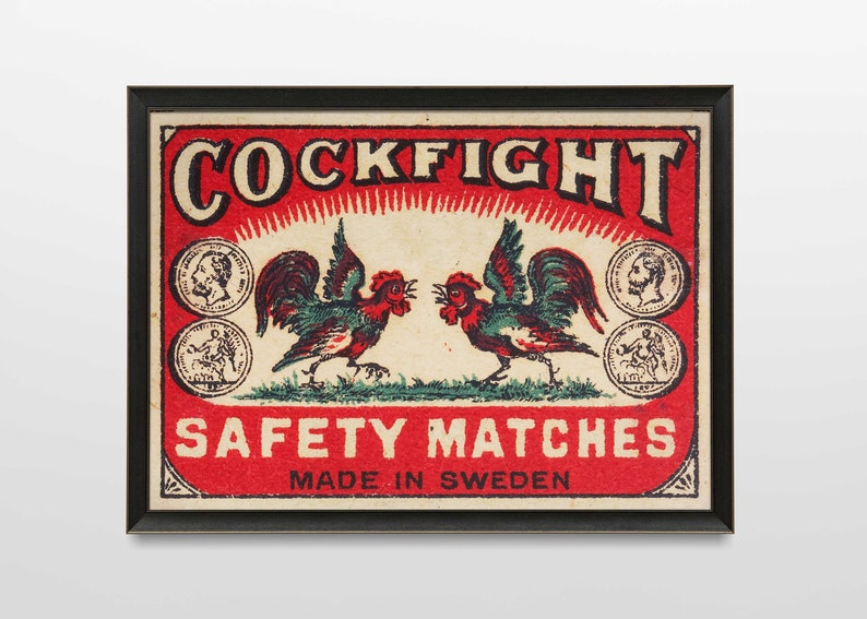 以下が含まれることがあります： 赤い背景に「COCKFIGHT SAFETY MATCHES MADE IN SWEDEN」という文字が書かれた、ビンテージのマッチ箱のラベル。2羽の雄鶏が向き合っていて、一方は緑と赤、もう一方は緑と青。雄鶏は小さな円形の画像で囲まれています。