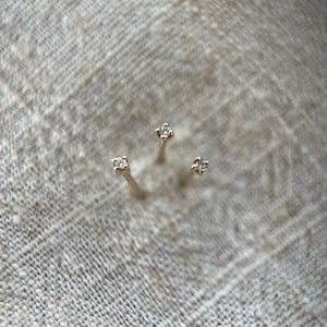 May include: Three gold stud earrings with small, clear diamonds.