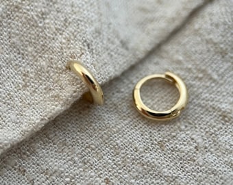 以下が含まれることがあります： 金色のフープイヤリングのペア。イヤリングは小さく繊細で、毎日の着用に最適です。