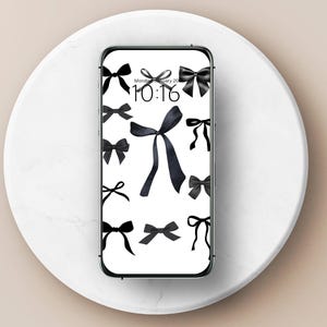 Op de afbeelding: Een zwart-wit telefoonscherm met een digitale klok die 10:16 laat zien en een patroon van zwarte strikken.