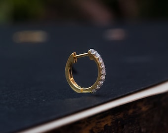 May include: A gold hoop earring with a row of small clear diamonds around the edge.