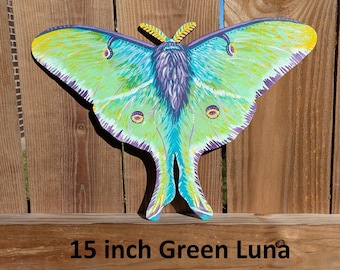 May include: A 15 inch green Luna moth painted on wood. The moth has a green body with yellow and blue accents. The wings are outlined in purple.