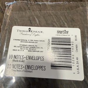 May include: A package of Thomas Kinkade "Heartline" note cards and envelopes. The label reads "10 NOTES &bull; ENVELOPES" and "Blank Inside." The package is sealed in clear plastic. The label also includes the text "A Holiday Gathering &copy; 1998 Thomas Kinkade."