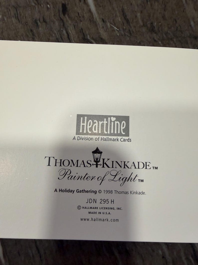 May include: A white card with the Heartline logo and text from Thomas Kinkade, "Painter of Light." The card includes the text "A Holiday Gathering &copy; 1998 Thomas Kinkade" and "Made in U.S.A."
