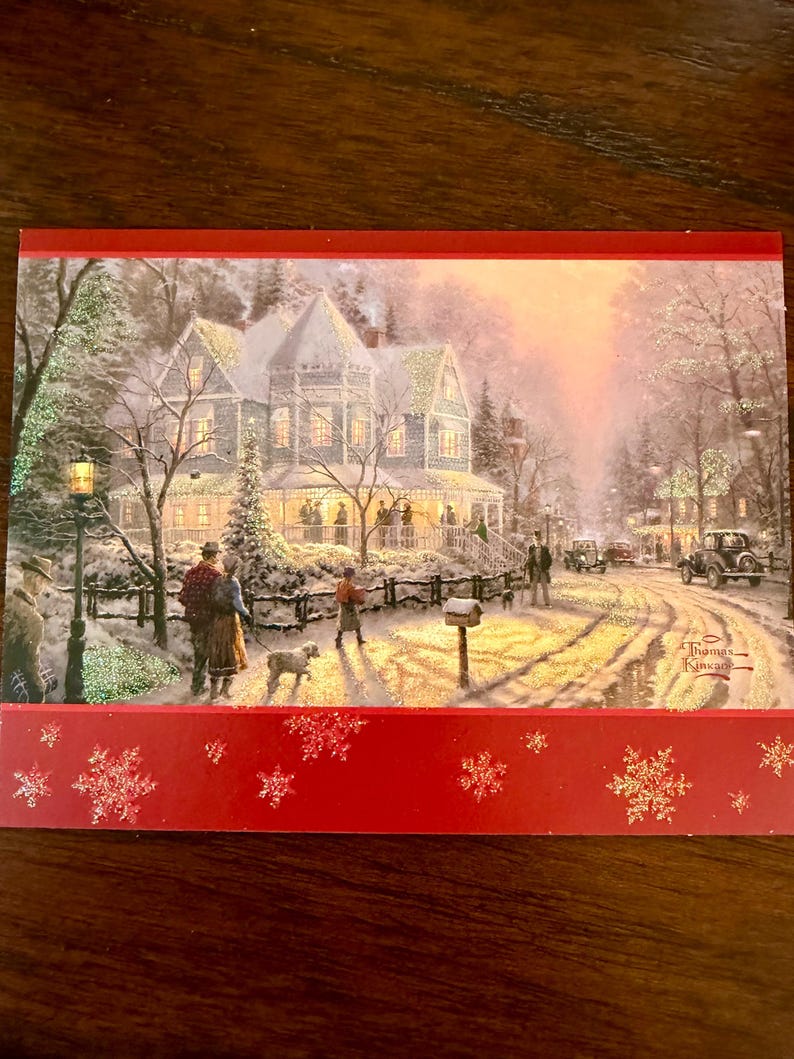 May include: A Christmas card featuring a winter scene with a snow-covered house, people, and vintage cars. The card has a red border with snowflake designs and the artist's signature.