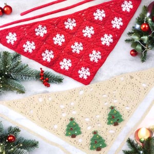 May include: Two crocheted triangular shawls, one red with white snowflakes and one beige with green Christmas trees. The shawls are laid out on a white surface with Christmas decorations.