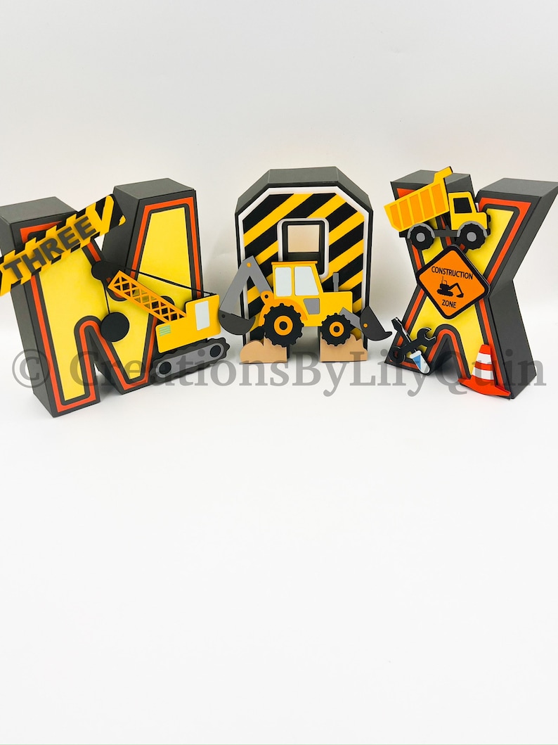 Pode incluir: Letras tridimensionais que soletram "MAX" em preto, amarelo e laranja. As letras s&atilde;o decoradas com ve&iacute;culos de constru&ccedil;&atilde;o e uma placa de "Zona de constru&ccedil;&atilde;o". As letras est&atilde;o sobre um fundo branco.