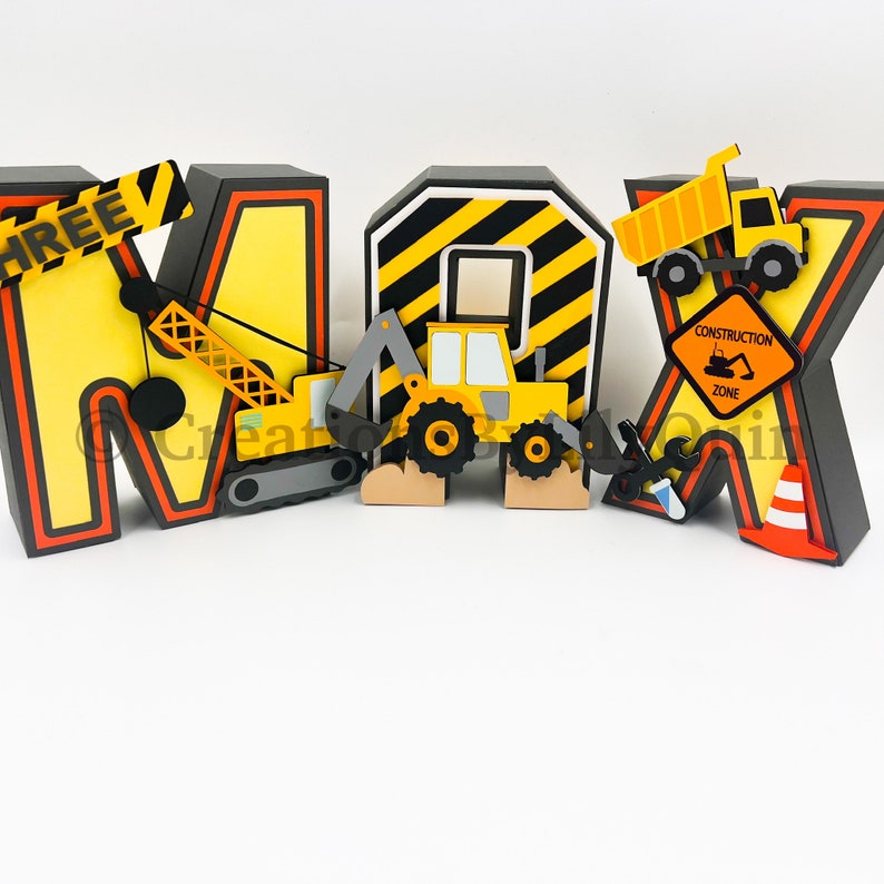 Pode incluir: Letras tridimensionais que soletram o nome "MAX" decoradas com ve&iacute;culos de constru&ccedil;&atilde;o e uma placa de zona de constru&ccedil;&atilde;o. As letras s&atilde;o amarelas com listras pretas e bordas pretas. Os ve&iacute;culos s&atilde;o amarelos e pretos. A placa &eacute; amarela com texto preto.