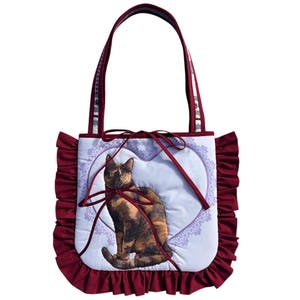 Puede incluir: Un letrero de madera rústico con la palabra "Welcome" en un estilo manuscrito. El letrero está pintado de blanco con un acabado envejecido, y un pequeño corazón decorativo está adjunto en la parte inferior. El fondo es una imagen borrosa de una superficie de madera.