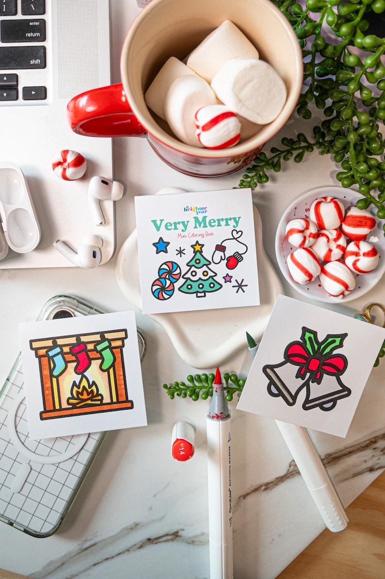 May include: Three square coloring cards featuring holiday illustrations. One card shows a fireplace with stockings, one shows two bells with a red bow, and the center card is titled Very Merry Mini Coloring Book with a tree, star, and mittens.