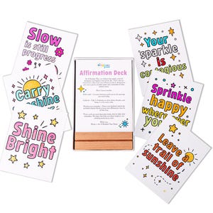 May include: An affirmation deck with colorful cards featuring inspirational phrases like "Shine Bright" and "Leave a trail of sunshine." The deck includes a wooden display stand and cards with star and sun illustrations.