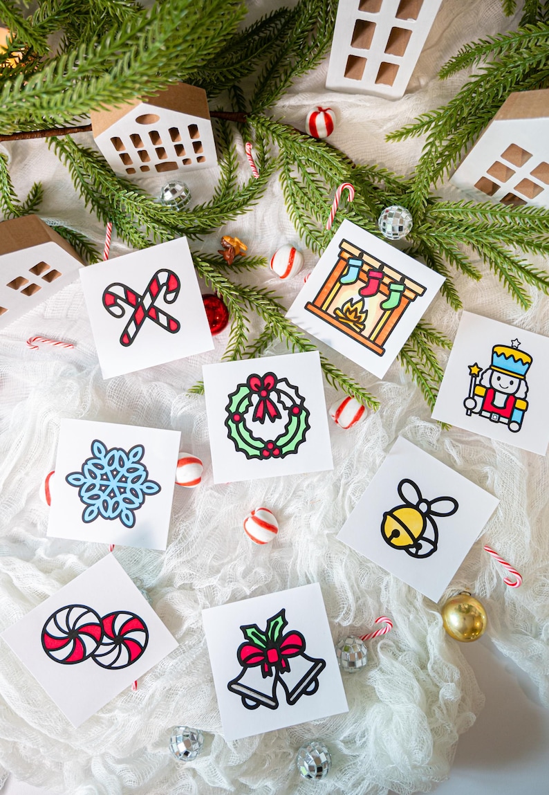 May include: A collection of eight square white cards featuring colorful Christmas illustrations including candy canes, a fireplace with stockings, a nutcracker, a snowflake, a wreath, a bell, peppermint candies, and two bells with a red bow.