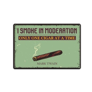 Może przedstawiać: Metalowy znak w stylu vintage z zielonym tłem i brązową ramką. Na znaku widnieje napis "Palę z umiarem, tylko jeden cygaro na raz, Mark Twain". Na znaku znajduje się kreskówkowa ilustracja zapalonego cygara z dymem.