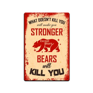Puede incluir: Un letrero metálico rectangular con un aspecto vintage y desgastado. El letrero presenta el texto "WHAT DOESN'T KILL YOU will make you STRONGER Except Bears BEARS will KILL YOU" con una ilustración de oso rojo.