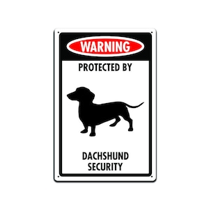 Puede incluir: Un cartel blanco con letras negras y rojas que dice "Advertencia Protegido por la seguridad del Dachshund". Una silueta negra de un dachshund está en el centro del cartel.