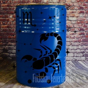 Può includere: Un barile di metallo blu con una silhouette nera di uno scorpione e la costellazione dello Scorpione. Il barile ha un punto nero e il testo "Fuchsbau Feuertonnen" sul fondo.