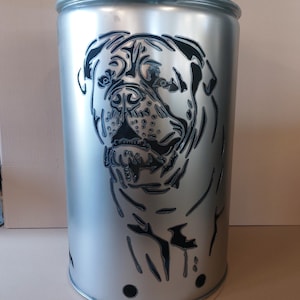 Può includere: Un braciere in metallo argentato con un designo a taglio di una testa di cane. La testa del cane è nera e il braciere ha tre piccoli fori sul fondo.