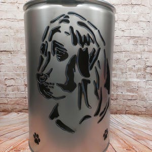 Può includere: Un braciere in metallo argentato con un design a forma di testa di cane tagliato. Il braciere ha un coperchio e tre impronte di zampe sul fondo.