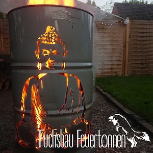 Può includere: Un focolare in metallo a forma di Buddha seduto con fiamme che bruciano all'interno. Il focolare è dipinto di grigio e ha il testo "Fuchsbau Feuertonnen" in basso.