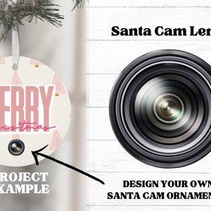 Puede incluir: Un adorno navideño redondo blanco con un diseño rosa de "Feliz Navidad" y una lente de cámara negra en el centro. El adorno está colgado de una cuerda blanca. El texto "Santa Cam Lens" está escrito en negro sobre una lente de cámara negra. El texto "¡Diseña tus propios adornos Santa Cam!" está escrito en negro debajo de la lente de cámara.