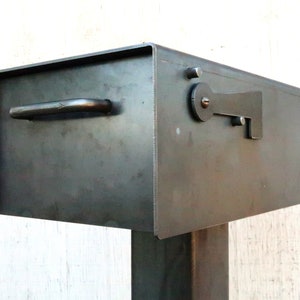 May include: A metal mailbox with a hinged door and a handle. The mailbox is mounted on a metal post.
