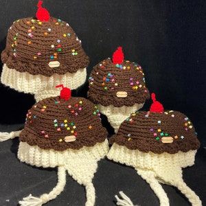May include: Three crocheted ice cream cone hats with white yarn and brown yarn for the ice cream. The hats have colourful sprinkles and a red cherry on top. Each hat has a brown tag that says "Handmade".