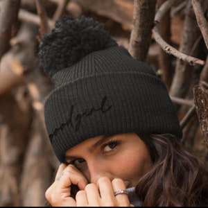 May include: Black knit beanie with a pom pom on top and the word "undisputed" embroidered in black on the front.