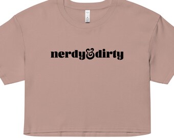 May include: A light pink cropped t-shirt with the text "nerdy & dirty" printed in black.