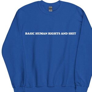 Könnte beinhalten: Königsblaues Sweatshirt mit dem weißen Text "BASIC HUMAN RIGHTS AND SHIT" auf der Brust. Das Sweatshirt hat einen Rundhalsausschnitt und lange Ärmel. Das Kleidungsstück ist aus weichem Material.