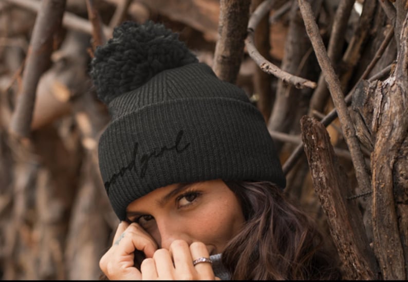Puede incluir: Gorro de punto negro con un pomp&oacute;n en la parte superior y la palabra "undisputed" bordada en negro en la parte delantera.