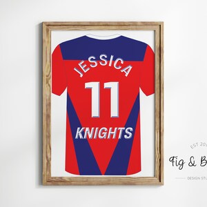 May include: A framed print of a red and blue jersey with the name "Jessica" and the number "11" on the back. The jersey also has the word "Knights" printed on the back. The frame is made of wood and has a light brown finish.