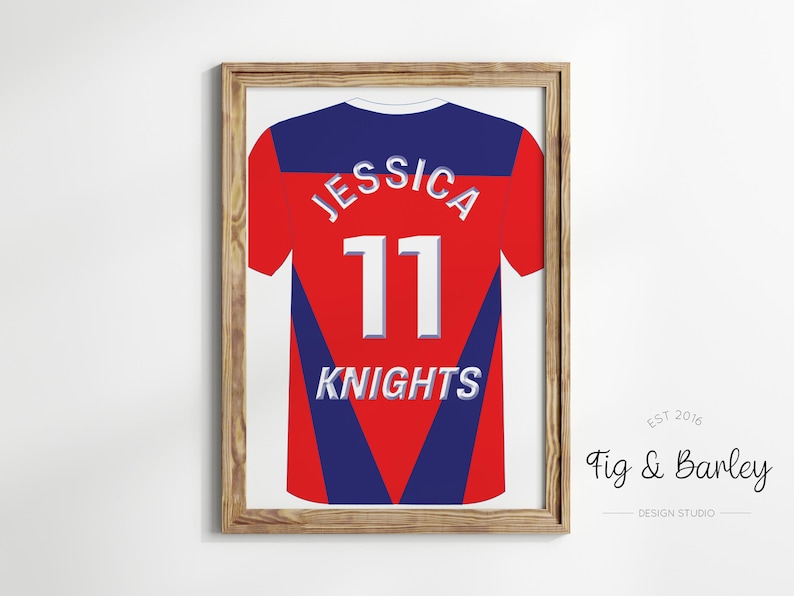 May include: A framed print of a red and blue jersey with the name "Jessica" and the number "11" on the back. The jersey also has the word "Knights" printed on the back. The frame is made of wood and has a light brown finish.