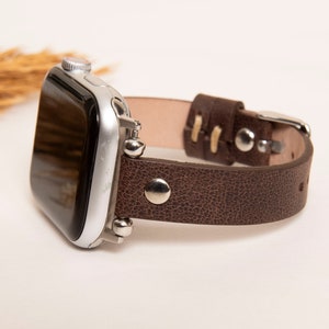 May include: A brown leather watch band with silver accents and a silver smartwatch.
