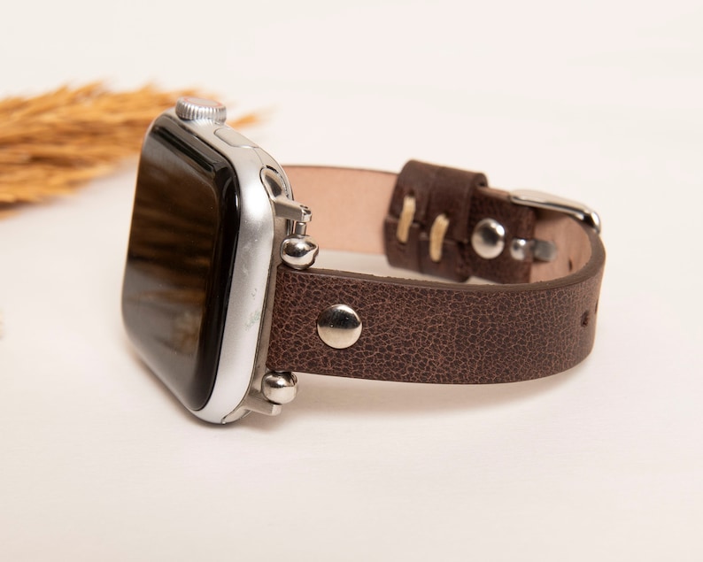 May include: A brown leather watch band with silver accents and a silver smartwatch.