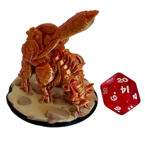 May include: A detailed, brown 3D-printed miniature of a mechanical creature, possibly for tabletop gaming. The figure is on a textured base, next to a red twenty-sided die. The creature has intricate mechanical details and red accents.