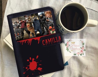Peut inclure: Un journal en cuir bleu foncé sur le thème de l'horreur. Le journal présente un collage de personnages de films d'horreur et le nom "Camilla" en rouge. Un motif d'éclaboussure rouge est sur le devant. Une tasse blanche avec du café est à côté du journal.