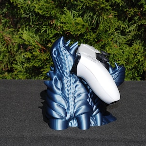Op de afbeelding: Een blauwe 3D-geprinte drakenstandaard met een witte videogamecontroller erop.