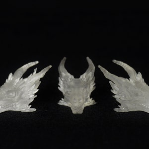 May include: Three translucent white dragon head sculptures, each with a different angle, are displayed against a black background.